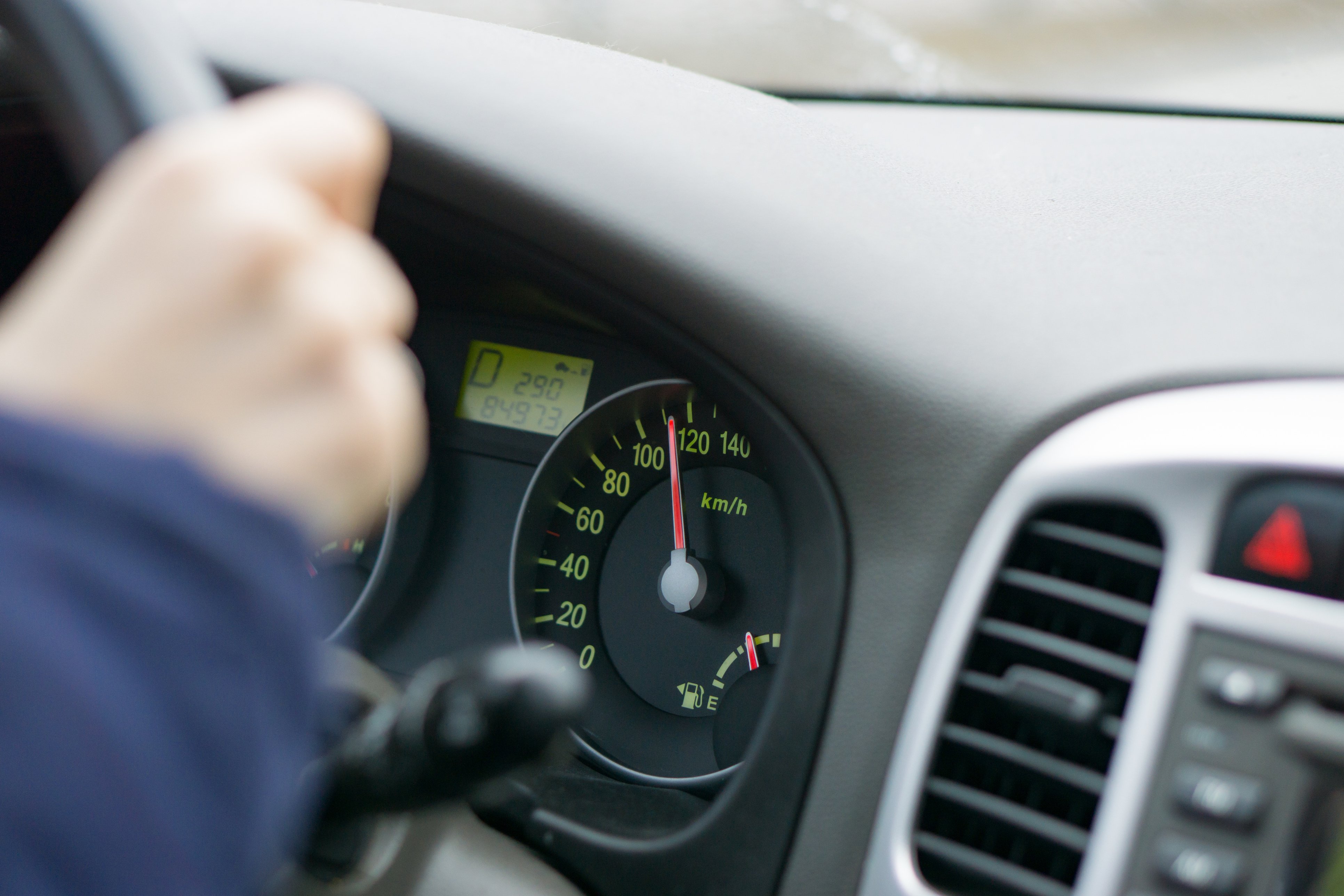 Picture of a driver with hands on the steering wheel and the kilometers at 120
