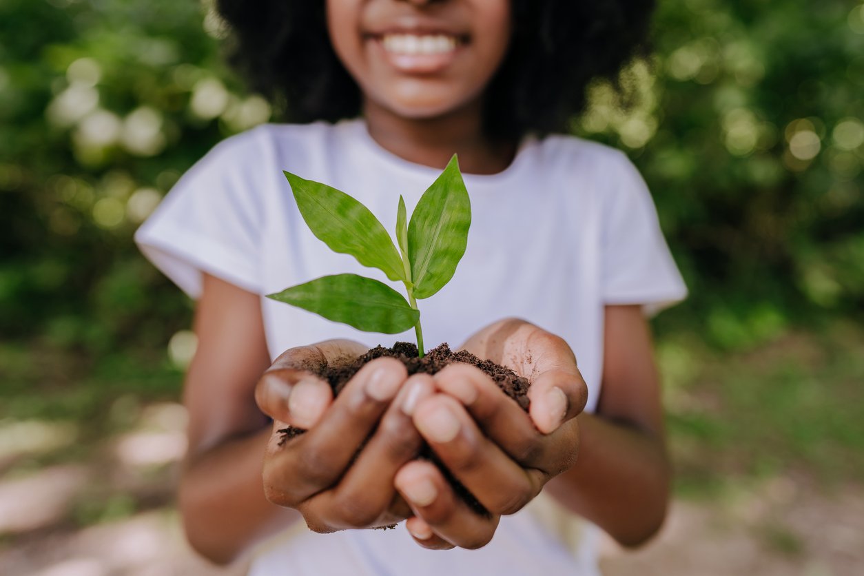 little girl holding a small plant in the palm of her hands